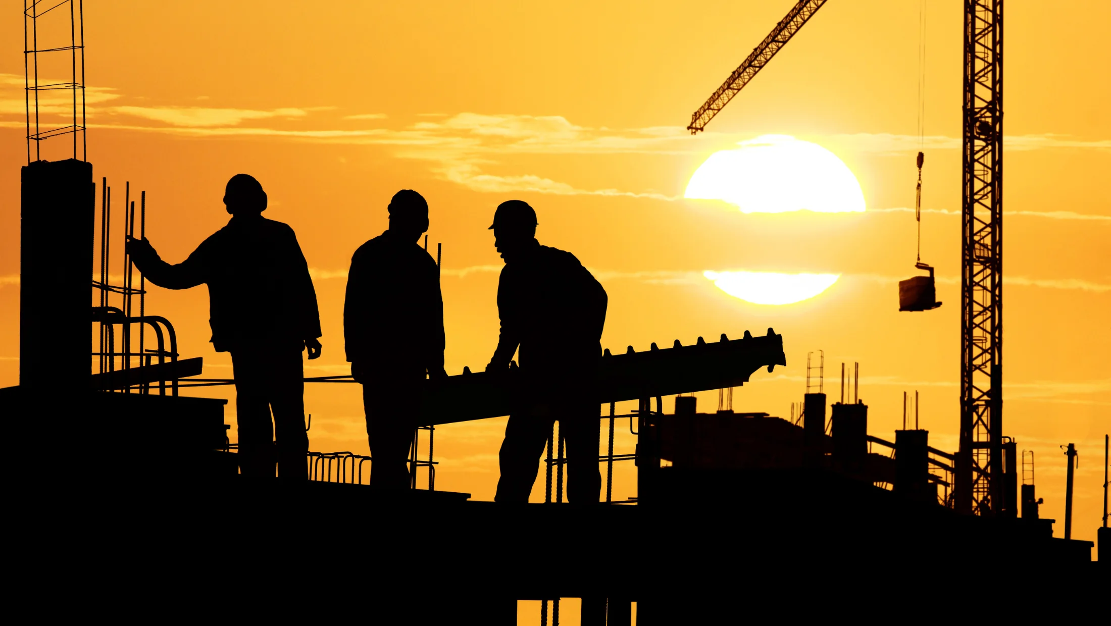 Construction workers on a site at sunset