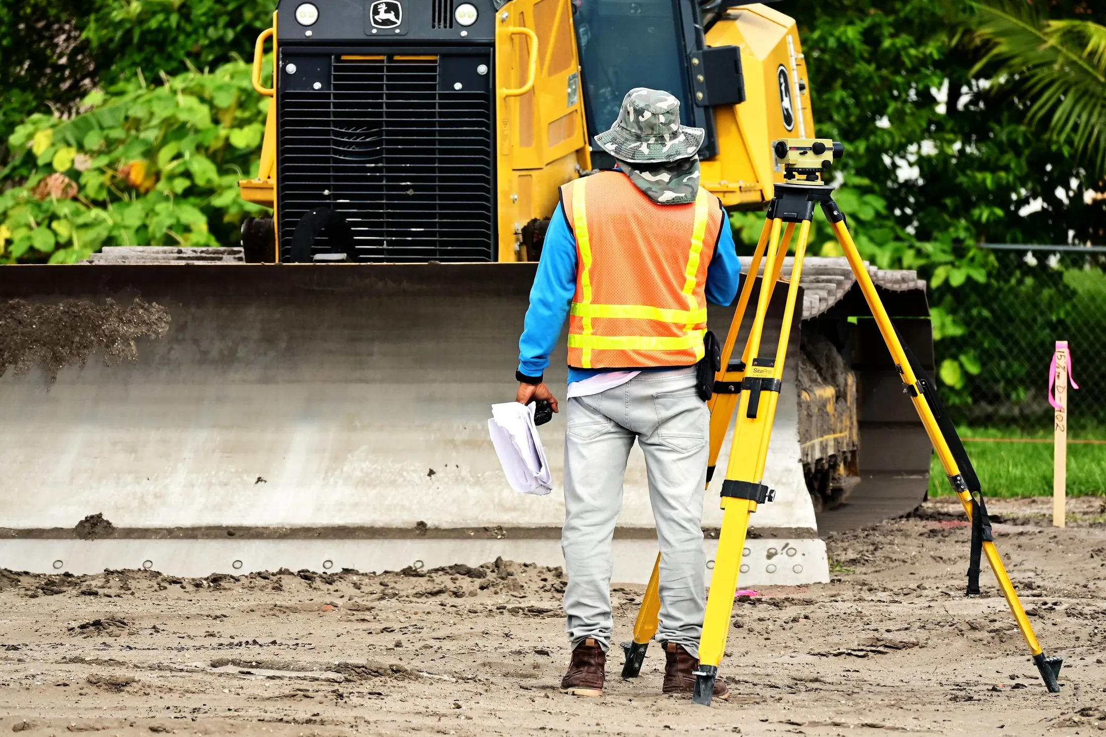 A surveyor taking measurements beside construction equipment
