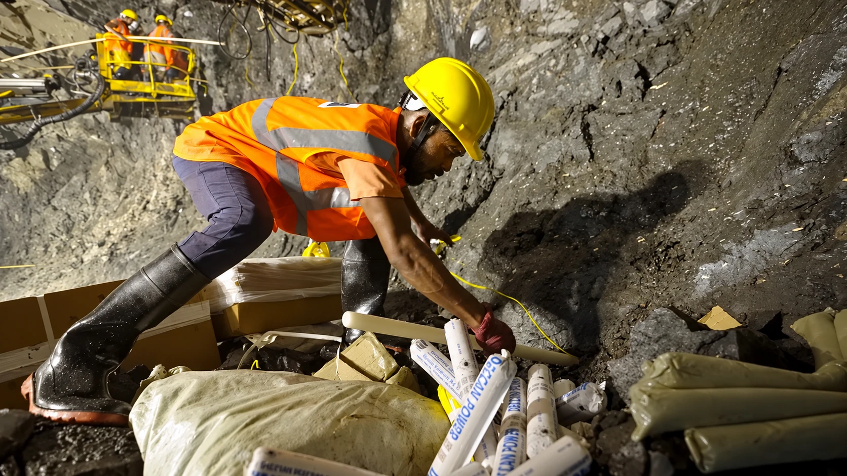 A crew charging blast holes at the tunnel face